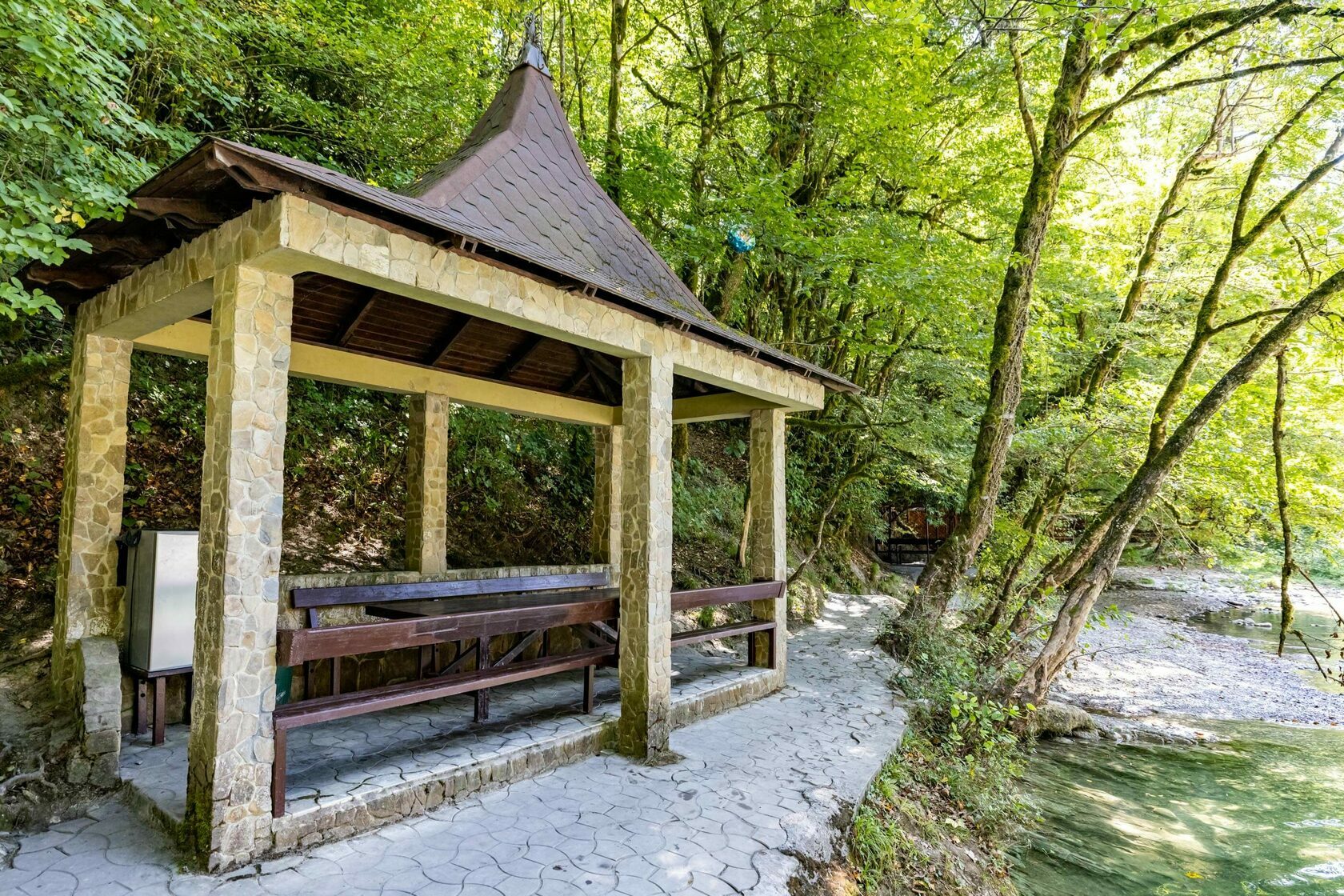 Каменная беседка у реки среди леса